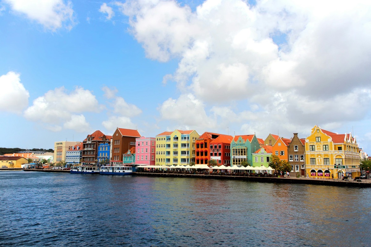 The Handelskade waterfront in Willemstad, Cura&ccedil;ao — a row of pastel Dutch colonial townhouses along the water.